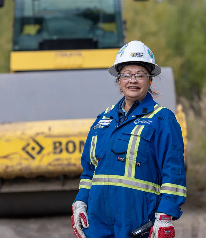 Samantha in coveralls with heavy equipment